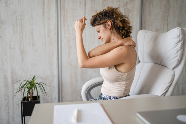Одна женщина фрилансер растягивается в офисе на работе, сидя в кресле за столом, используя ноутбук с болью в спине страдает от боли в шее, переутомления концепции копирования пространства - Фото, изображение