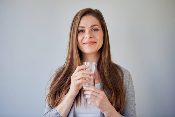 Smiling woman holding water glass in front off. isolated portrait of girl with long hair. - Photo, image