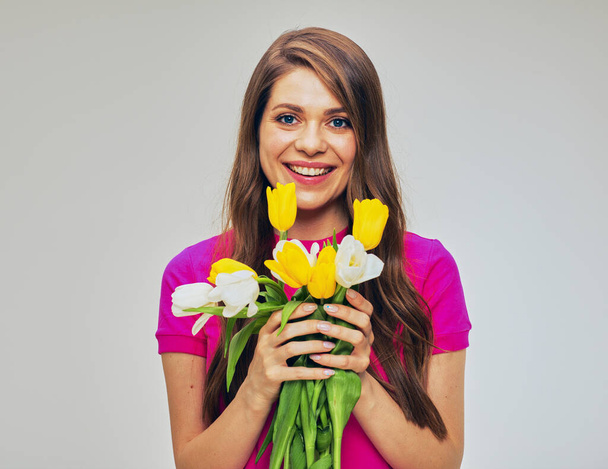 Young woman in red holding flowers bouquet in front of face. Isolated female studio portrait. - 写真・画像