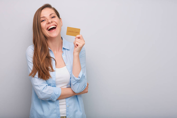Credit card in hand of smiling woman with long hair dressed blue white shirt isolated portrait   - Fotografie, Obrázek