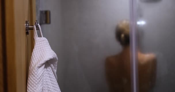 女性は、ホテルのシャワー、背中からのクローズアップビューで自分自身を洗っている。シャワー後の快適な服 - 映像、動画