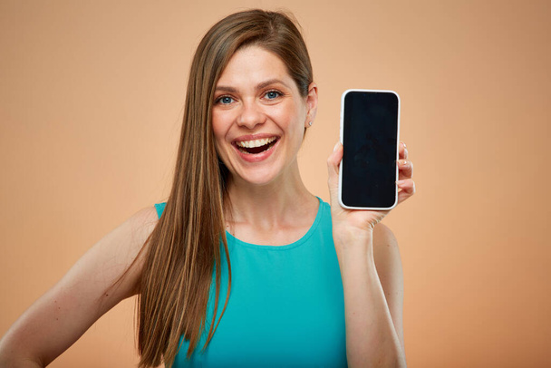 Happy woman holding smartphone with big screen, isolated portrait on yellow brown background. - Foto, immagini