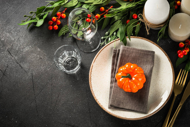 Herfsttafel met bord, bestek, pompoen en kaarsen. Thanksgiving eten feestelijk diner concept. Bovenaanzicht aan zwarte tafel. - Foto, afbeelding