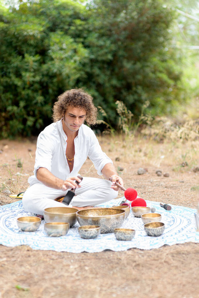 Muž, který si hraje na holubníku a zpívá si venku na meditaci. Buddhistické léčebné postupy. Zvuková terapie, alternativní medicína. Vyčistit prostor od negativní energie. Selektivní zaměření - Fotografie, Obrázek