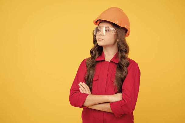 serious teenager girl in protective eyeglasses and helmet, copy space, building. - Фото, изображение