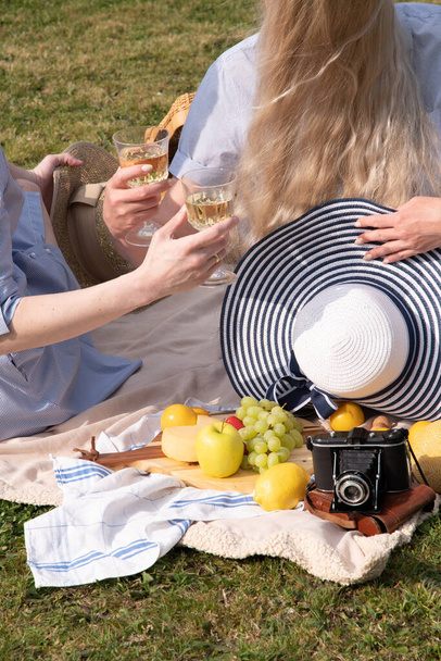 a two young women in a summer long dresses is resting on a picnic, a Blanket with cheese plate and fruits, rest from worries and household chores, parks and recreation areas,.High quality photo - Foto, Imagem