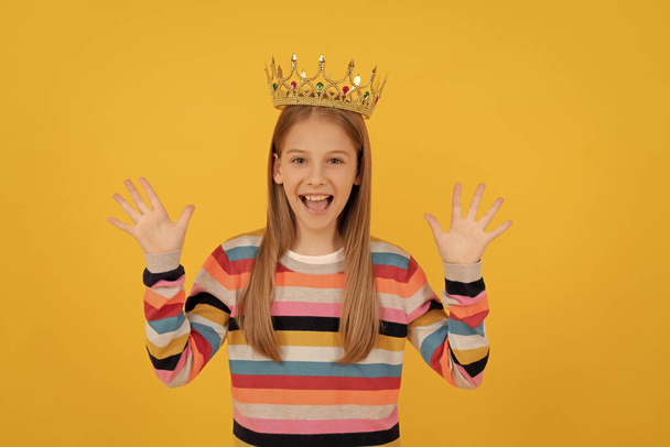 glad teen child in queen crown on yellow background. - Zdjęcie, obraz