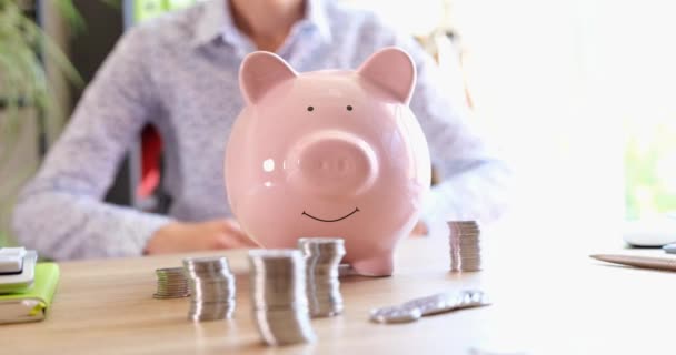 A woman holds her hands over a pink piggy bank, close-up. Financial protection, global crisis, family savings - Footage, Video