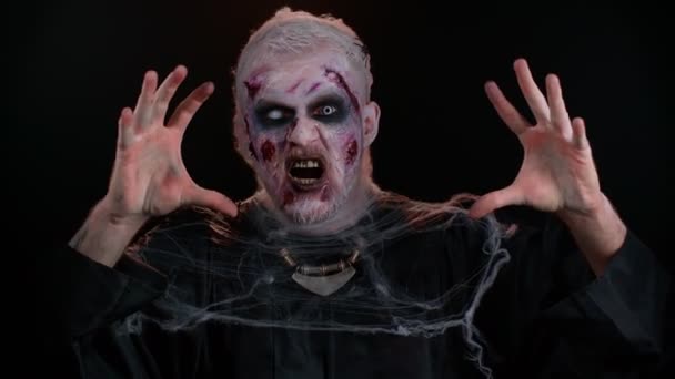 Karmiva mies veriset arvet kasvot, Halloween tyylikäs zombie meikki. Pelottava haavoittunut epäkuollut mies irvistelee, katsoo kameraan ja hymyilee kauheasti. Voodoorituaaleja. Teemajuhlat. Pahaenteinen peto, hirviö - Materiaali, video