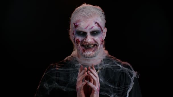 Kanlı suratlı ürkütücü adam, Cadılar Bayramı stili zombi makyajı. Korkunç yaralı ölümsüz adam yüzünü ekşitti, kameraya baktı ve korkunç bir şekilde gülümsedi. Voodoo ayinleri. Tematik parti. Şeytani canavar, canavar. - Video, Çekim