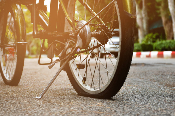 Vista de perto da roda traseira da bicicleta velha que é plana e estacionada no pavimento no parque público, foco suave e seletivo. - Foto, Imagem