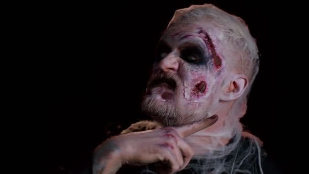 Zlověstný muž s děsivým Halloween zombie make-up v kostýmech dělat obličeje, dívat se zlověstně do kamery, ukazovat vražedné gesto v policejních světel, snaží se vystrašit. Mrtvý chlap se zraněným obličejem - Záběry, video