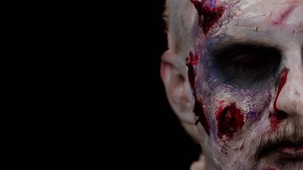 Detailní makro děsí člověka tváří v tvář Halloween zombie krvavý zraněný make-up, snaží se vystrašit, tvář výrazy. Hororové téma. Zlověstný nemrtvý chlap izolovaný na černém pozadí studia. Módní umění - Záběry, video