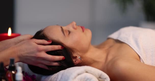 Mentir hermosa mujer es recibir un masaje en la cabeza, de cerca. Servicios médicos cosméticos en el salón - Imágenes, Vídeo