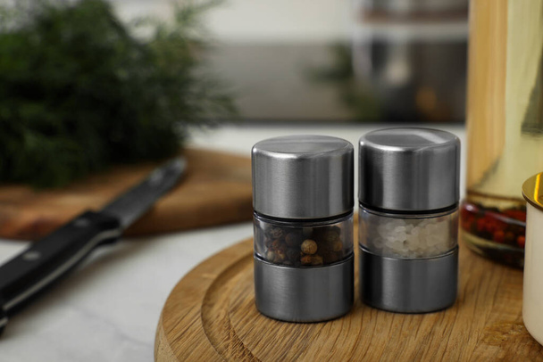 Salt and pepper mills on wooden board in kitchen. Space for text - Фото, изображение