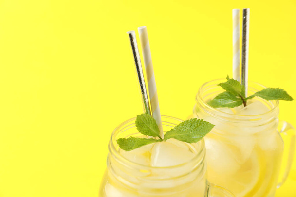 Natural freshly made lemonade with mint on yellow background, closeup. Summer refreshing drink - Zdjęcie, obraz