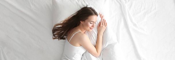 Young woman sleeping on comfortable pillow in bed at home, top view. Banner design - Foto, Bild