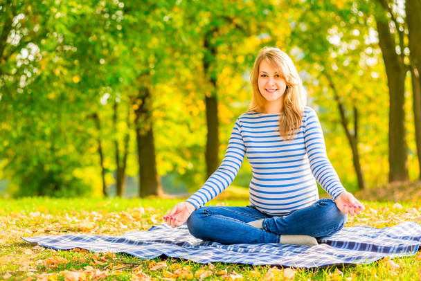 fröhliche Schwangere im Park sitzt im Lotus positio - Foto, Bild