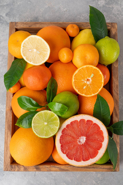 具体的な背景に木の箱に葉を持つ異なる柑橘類。健康食品。トップ表示. - 写真・画像