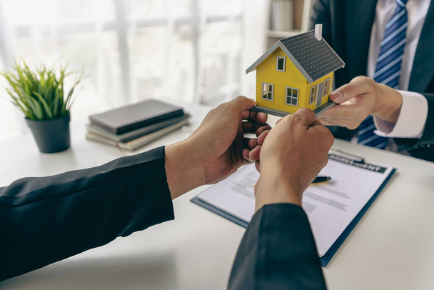 住宅エージェントは、新しい住宅購入者と話をし、良い金利を提供し、不動産の概念の決定を助けるために住宅ローン融資のクライアントを計算. - 写真・画像