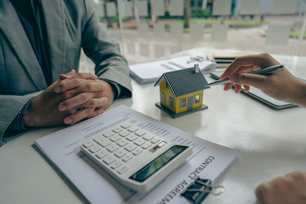 Les agents immobiliers parlent aux acheteurs de maisons neuves et offrent de bons taux d'intérêt et calculent les clients sur le financement hypothécaire pour les aider à prendre des décisions de concept immobilier. - Photo, image
