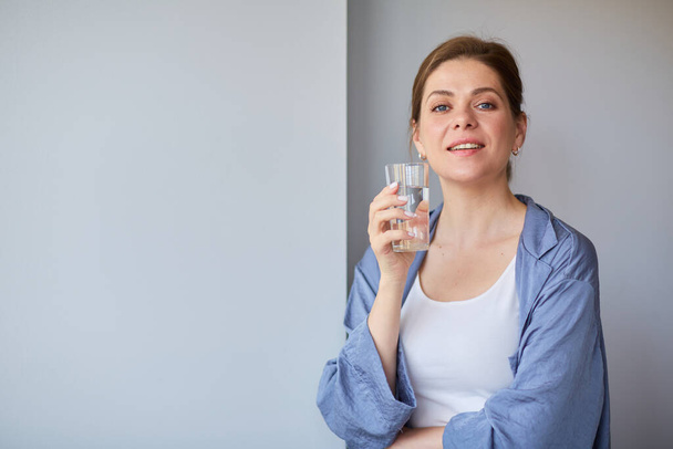 Mujer sonriente sosteniendo un vaso de agua. Estilo de vida casual. - Foto, Imagen
