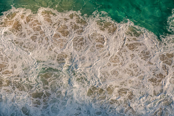 Vista superior de los patrones de espuma blanca del impacto de las olas oceánicas en las rocas costeras. Sudafrica - Foto, imagen