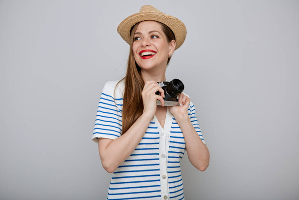 Traveling smiling woman isolated portrait. Girl in white dress and summer hat holding photo camera and looking back over shoulder. - Fotografie, Obrázek