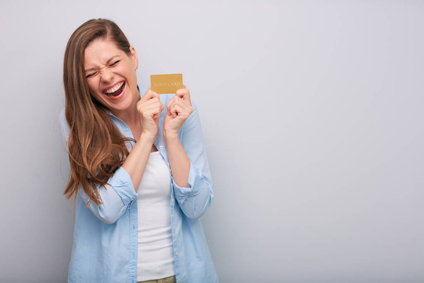 Credit card in hand of happy laughing woman with closed eyes dressed blue white shirt isolated portrait   - Foto, immagini