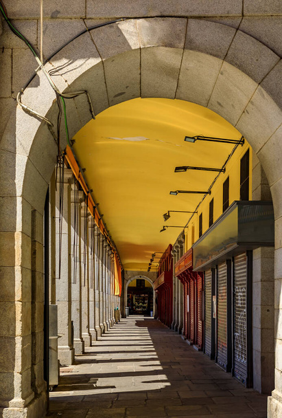 Arcade a lo largo de la Plaza Mayor que alberga cafeterías y restaurantes cerrados por el día en Madrid, España - Foto, imagen