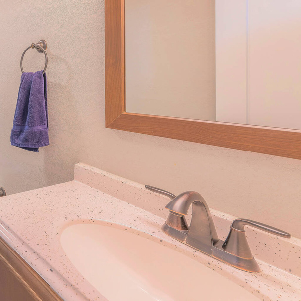 Salle de bain carrée intérieure avec carrelage gris et vanité avec dessus en granit et miroir encadré. Il y a un bol de toilette près de la baignoire avec des carreaux à motifs en bois entourent et rideau de douche en plastique. - Photo, image