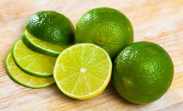 Picture of cut fresh raw green limes on wooden table in home kitchen - Photo, Image