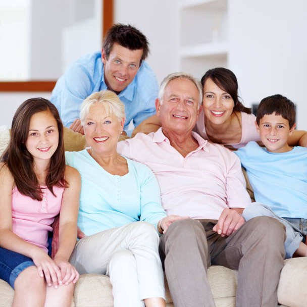 Ylpeä, rakastava perhe nauttimassa yhteisestä ajasta. Kolmen sukupolven perhe syleilee toisiaan sohvalla. - Valokuva, kuva