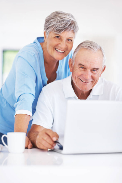 Happy mature couple using laptop at home. Portrait of smiling mature couple using laptop at home - Valokuva, kuva