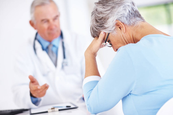 Médico maduro con paciente infeliz. Médico maduro discutiendo informe médico con paciente mujer infeliz - Foto, imagen