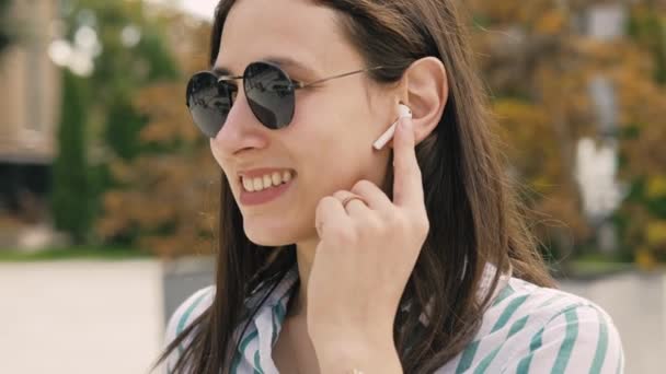Footage of young casual woman using earpods and answering at phone call. - Footage, Video