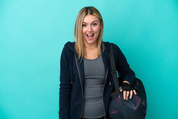 Young sport woman with sport bag isolated on blue background with surprise facial expression - Photo, Image