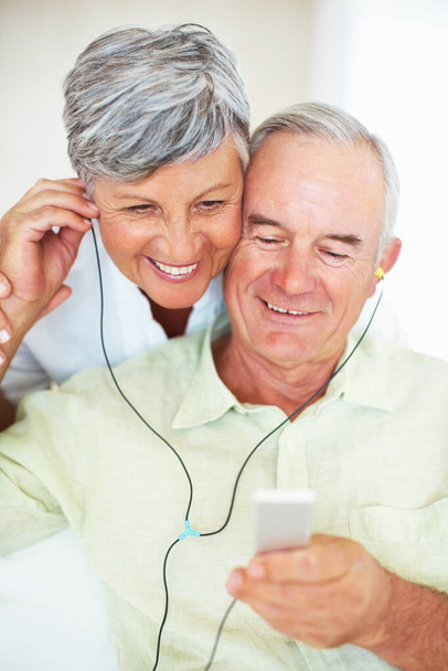 Зрелая пара слушает музыку дома. Красивый взрослый мужчина и женщина слушают музыку дома - Фото, изображение