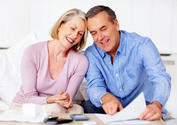 An attractive senior couple calculating their home expenses. Portrait of an attractive senior couple calculating their home expenses - Foto, Bild