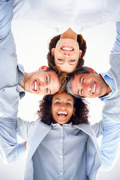 Business group in a huddle. Low angle view of business group in a huddle smiling and looking at you - Foto, Imagem