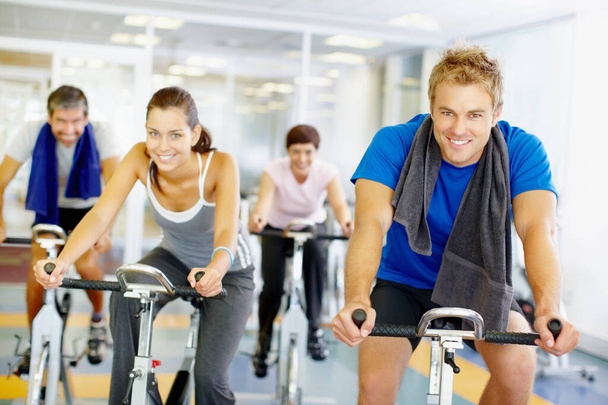 Ομαδική άσκηση. Ομάδα ανθρώπων που χρησιμοποιούν ποδήλατα γυμναστικής στο γυμναστήριο - Φωτογραφία, εικόνα