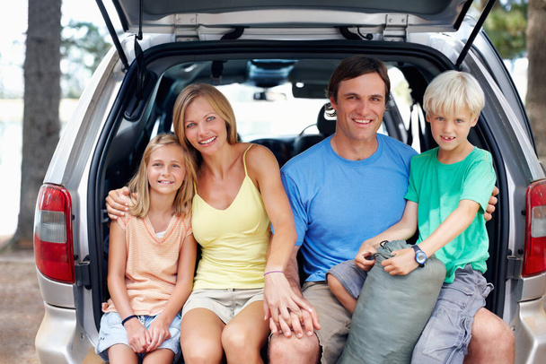 Attraktive Familie, die im Fond eines Autos sitzt und lächelt. Porträt einer attraktiven vierköpfigen Familie, die im Auto sitzt und ihren Urlaub genießt - Foto, Bild
