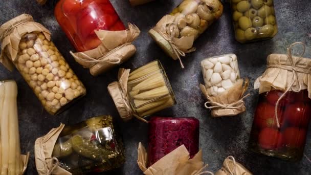 Closed pickling jars with various vegetables on stone table. Top view, flat lay - Footage, Video