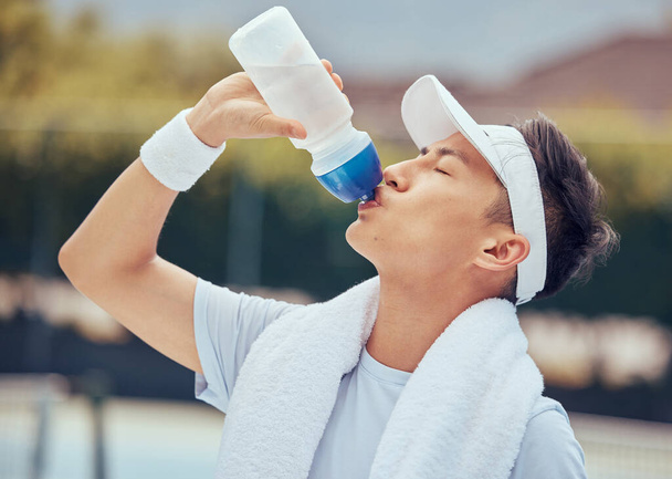 Asian man drinking water, fitness and relax after a training session, workout or exercise. Athlete, health and sports male resting with refreshing liquid after playing a sport, cardio or running - Zdjęcie, obraz