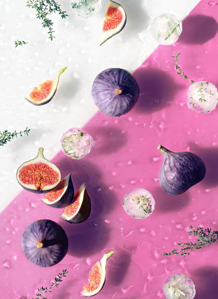 Water background with fresh ripe fig fruits and slices swimming in water. Ice balls with herbs, drops on wet pink background. Natural direct sunlight with shadows. - Photo, Image