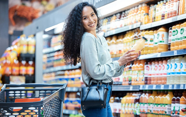 Retrato de una mujer con jugo mientras compra en una tienda de comestibles con una venta de productos al por menor. Cliente feliz con un estilo de vida de bienestar, salud y dieta comprando alimentos saludables en un supermercado - Foto, Imagen