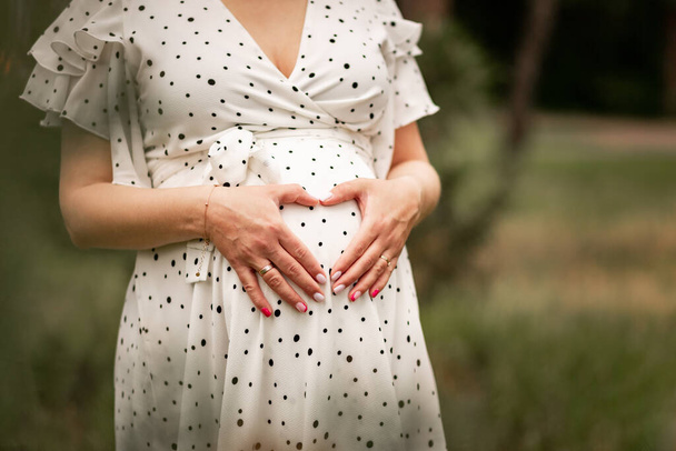 oříznutý záběr těhotné ženy držící ruce na břiše - Fotografie, Obrázek