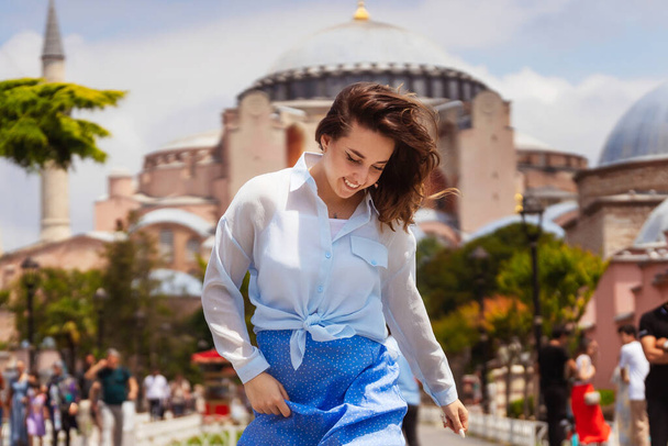 Caminin arka planında mavi etekli Avrupalı bir kız. İstanbul 'da, Hagia Sou' nun arka planında bir kızın fotoğraf çekimi. İstanbul 'da bir turistin fotoğrafı ilgi odağı oldu - Fotoğraf, Görsel