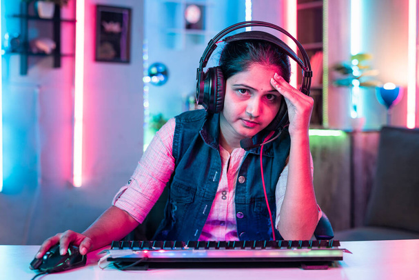 worried gamer with headphone due to loss while playing online video game by looking camera at home - concept of live streamer, leisure activities and online gaming tournament - Foto, imagen