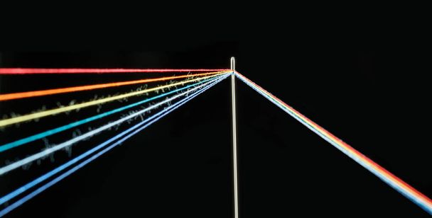multi-colored threads for sewing in the form of a rainbow pass through an antique needle on a black background close-up - Foto, Imagen
